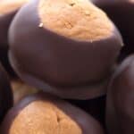 Titled image close up of keto chocolate dipped peanut butter balls in a bowl.