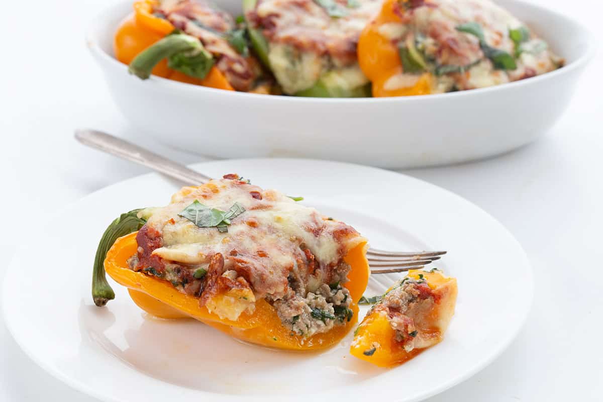 A close up shot of keto stuffed peppers on a white plate with a fork.
