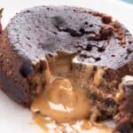 Titled Pinterest image of molten peanut butter oozing out of a chocolate lava cake on a white plate.