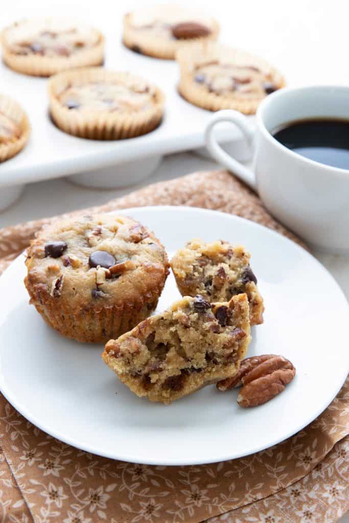 Two keto pecan pie muffins on a white plate over a brown patterned napkin.