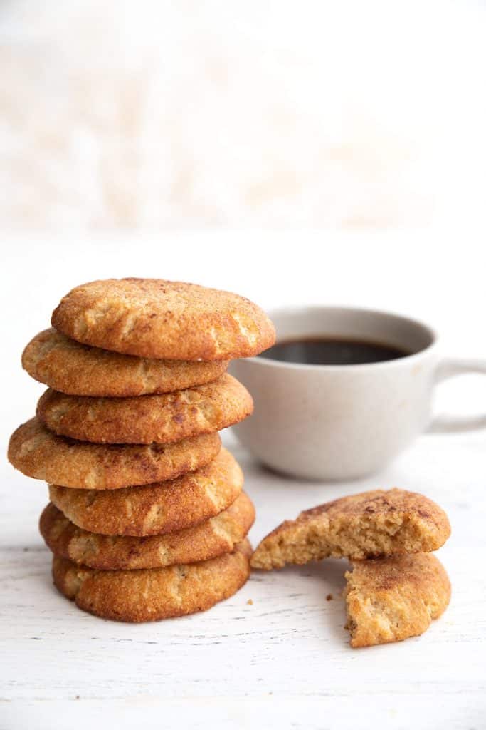 A stack of keto snickerdoodle cookies with a cup of coffee in the background.