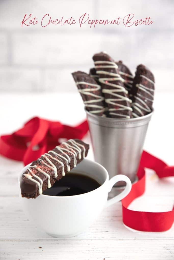 Keto Chocolate Peppermint Biscotti sitting on a white cup of coffee with more biscotti in the background.