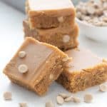 Keto peanut butter blondies in a pile in front of a bowl of sugar free peanut butter chips.