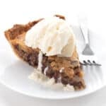 A slice of Keto Kentucky Derby Pie on a white plate with a scoop of ice cream on top.