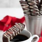 Titled image of keto peppermint biscotti, with one balanced on a white coffee cup, on a white wooden table.