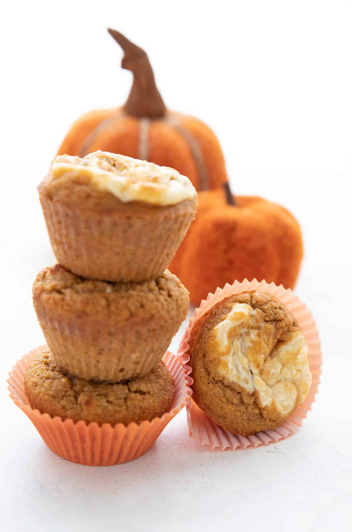 A stack of keto pumpkin muffins in front of two felt pumpkins. 