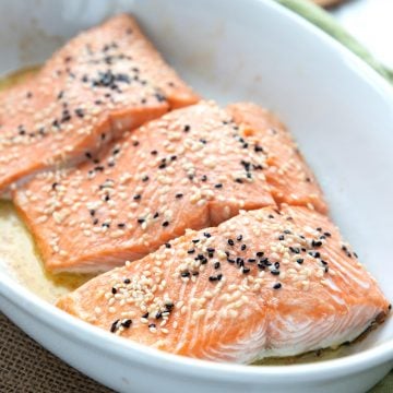 Keto oven roasted salmon in a white dish with sesame seeds on top.