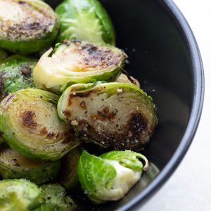 A black bowl filled with caramelized Brussels sprouts.