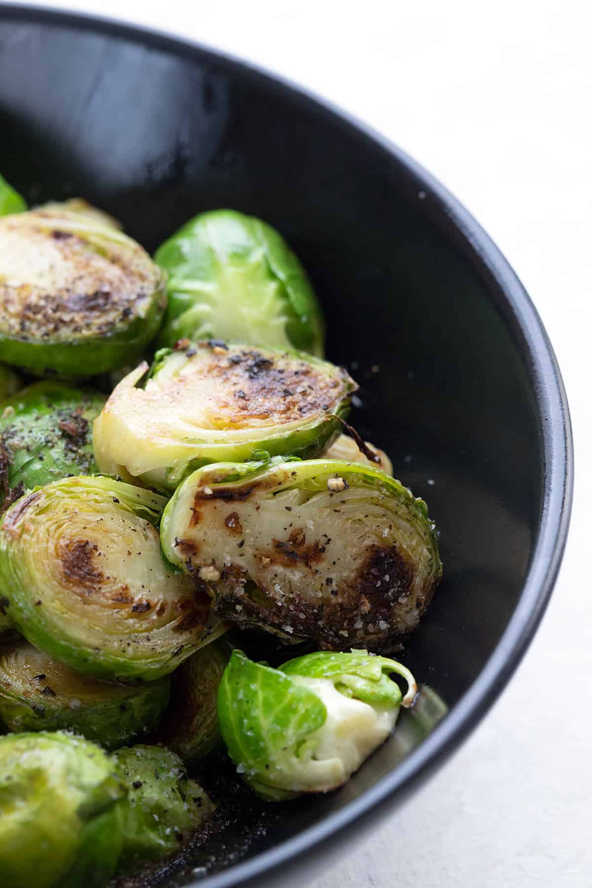 Close up shot of Brussels sprouts in a black bowl.