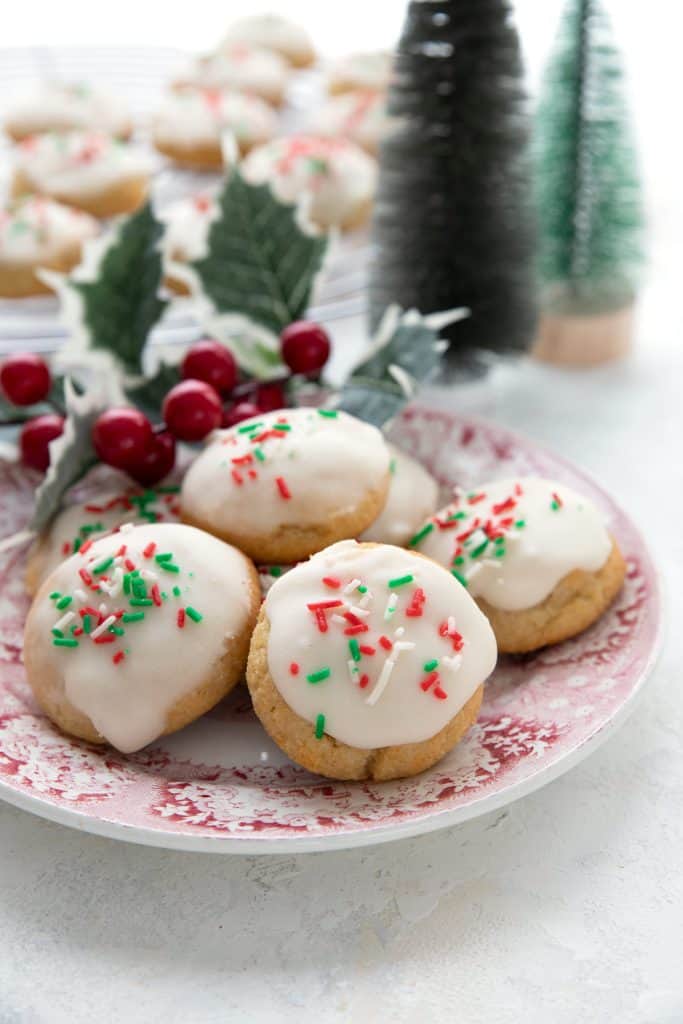 A plate of keto Italian ricotta cookies with holiday decorations in the background.