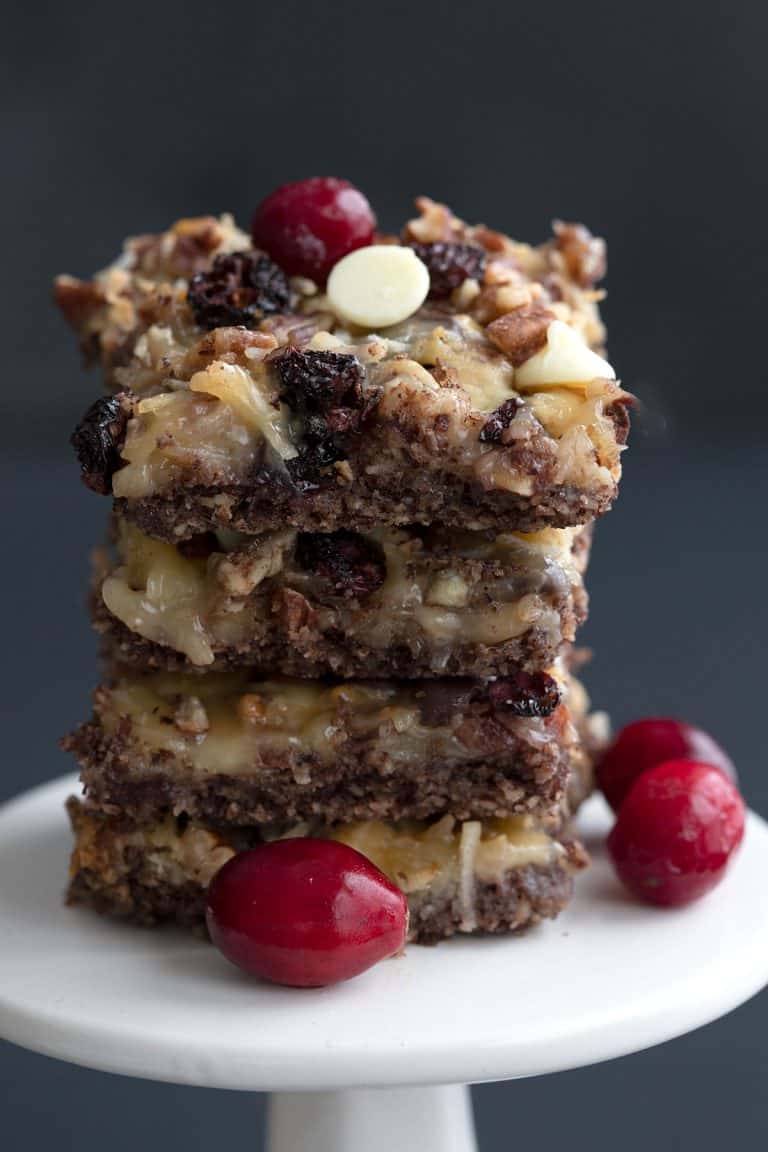 A stack of keto cranberry magic bars on a white cake stand.