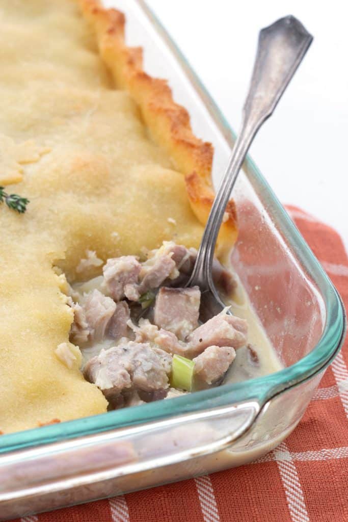 Keto turkey pot pie in a glass baking dish with a spoon digging into the filling.