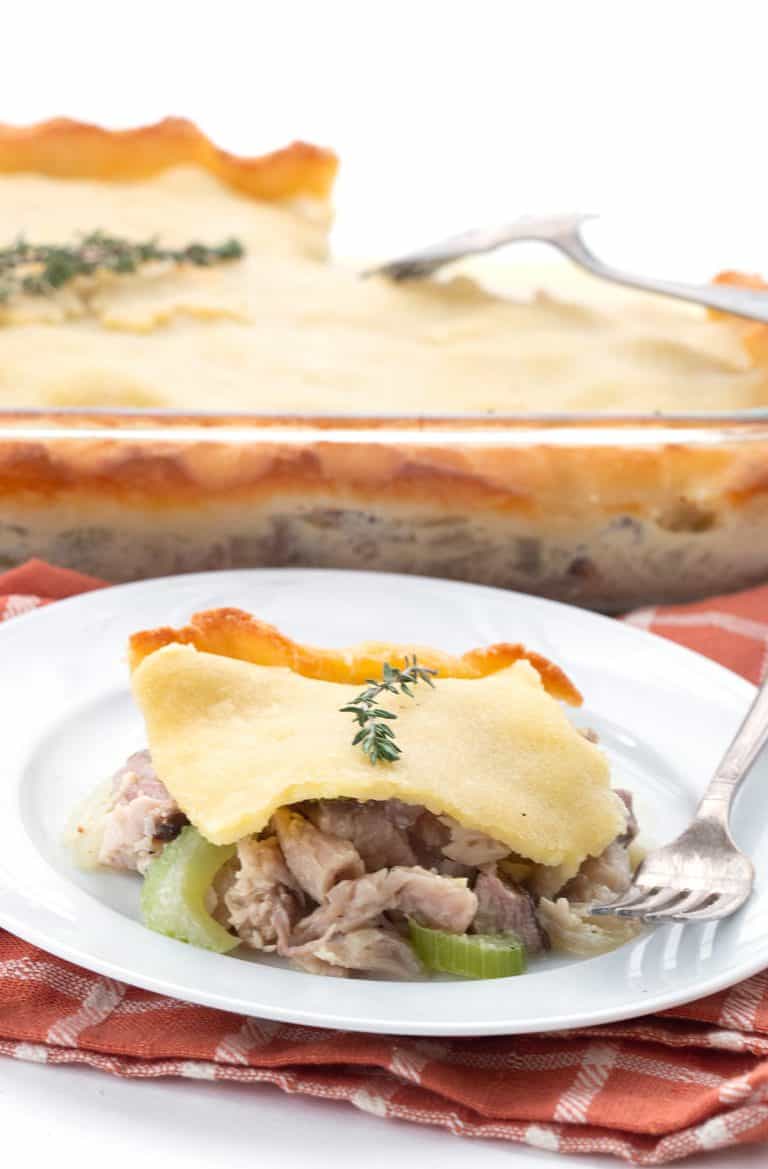 A serving of turkey pot pie on a white plate over an orange plaid napkin.