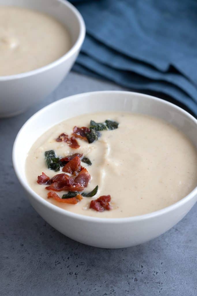 Close up shot of roasted cauliflower soup with crispy prosciutto and sage on top.