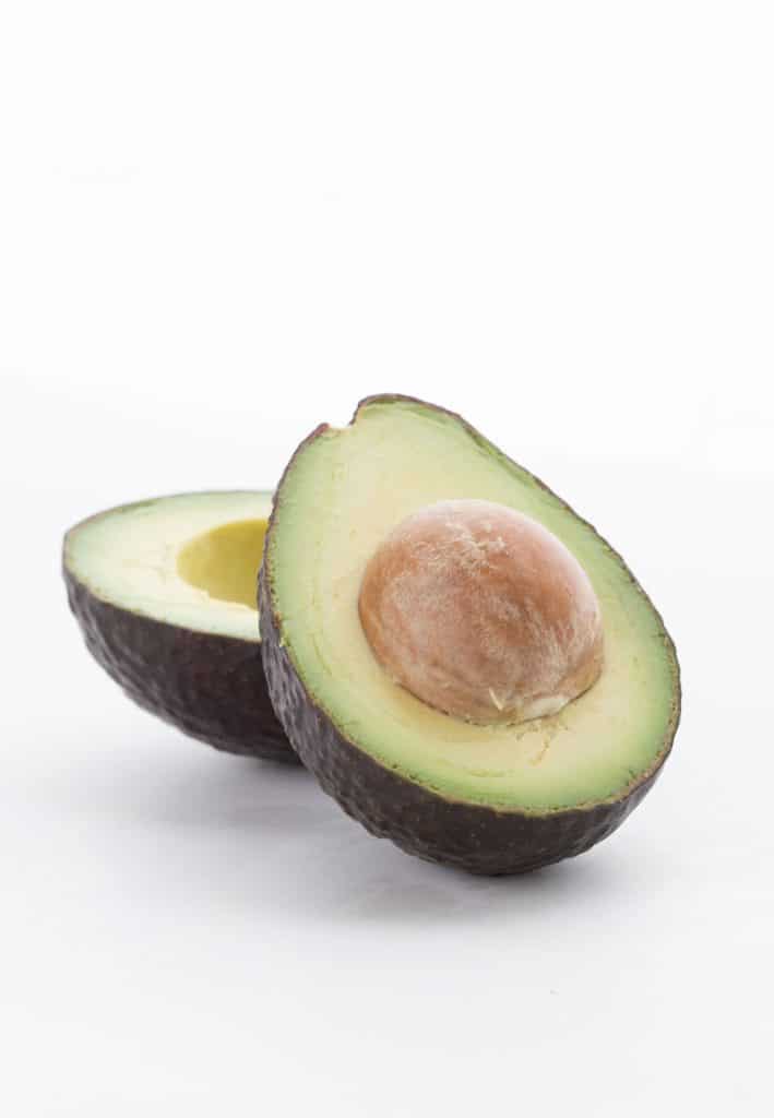 An avocado cut open on a white background.