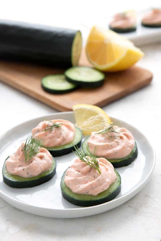 A small white plate full of smoked salmon mousse on cucumber slices.