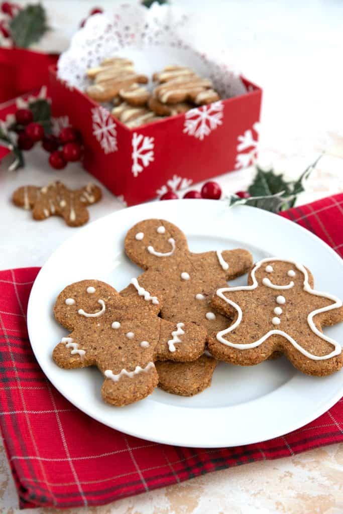 Three sugar-free keto gingerbread cookies on a white plate over a red plaid napkin.