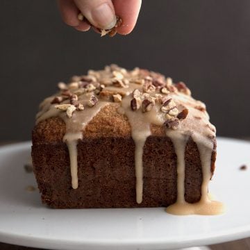 Sprinkling toasted pecans over the top of a keto rum cake.