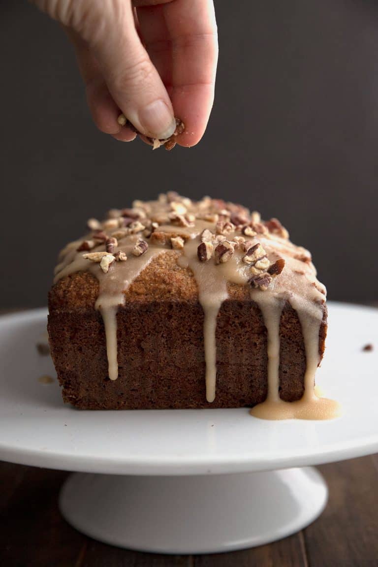 Sprinkling toasted pecans over the top of a keto rum cake.