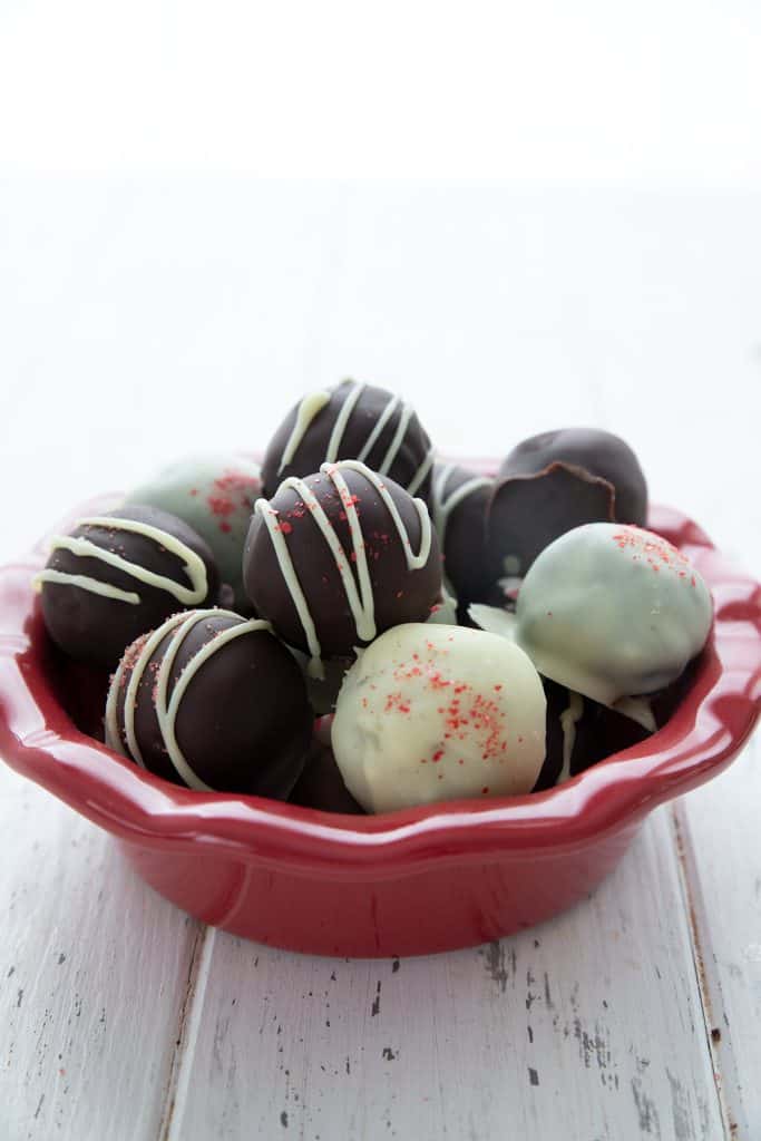 A red bowl filled with keto peppermint truffles dipped in white and dark sugar-free chocolate. 