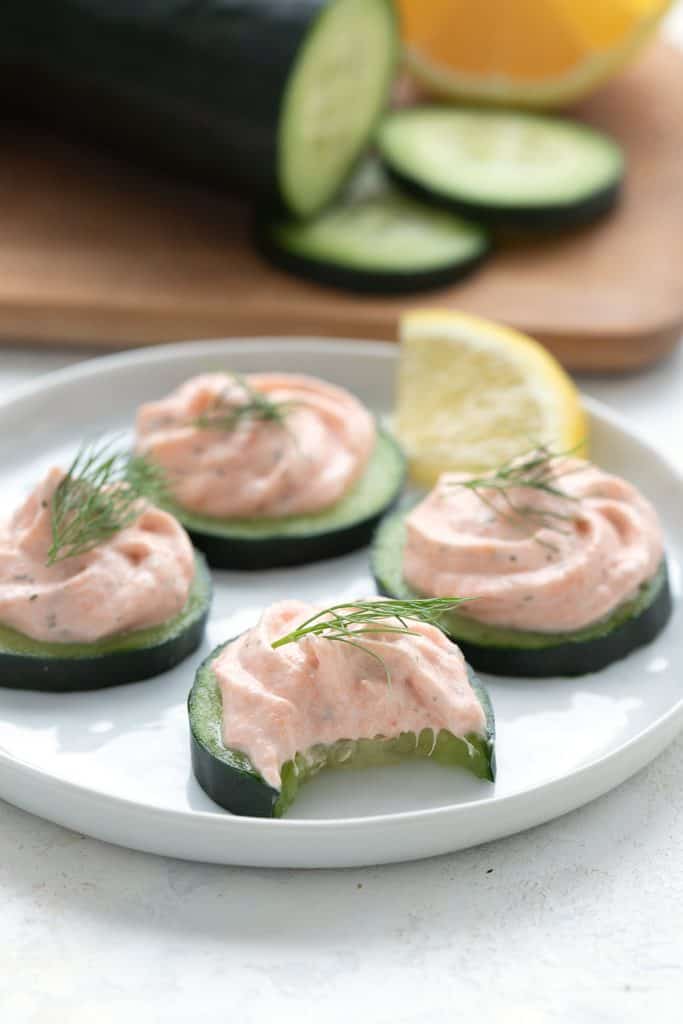 Easy smoked salmon mousse on cucumber rounds on a white plate.