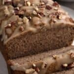 Titled image of a loaf of keto rum pound cake with two slices cut out and a glaze with chopped pecans on top.