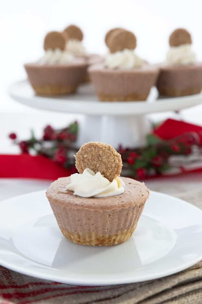 A mini keto gingerbread cheesecake on a white plate with more cheesecakes in the background.