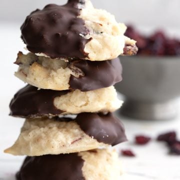 A stack of keto macaroons in front of a bowl of sugar-free dried cranberries.