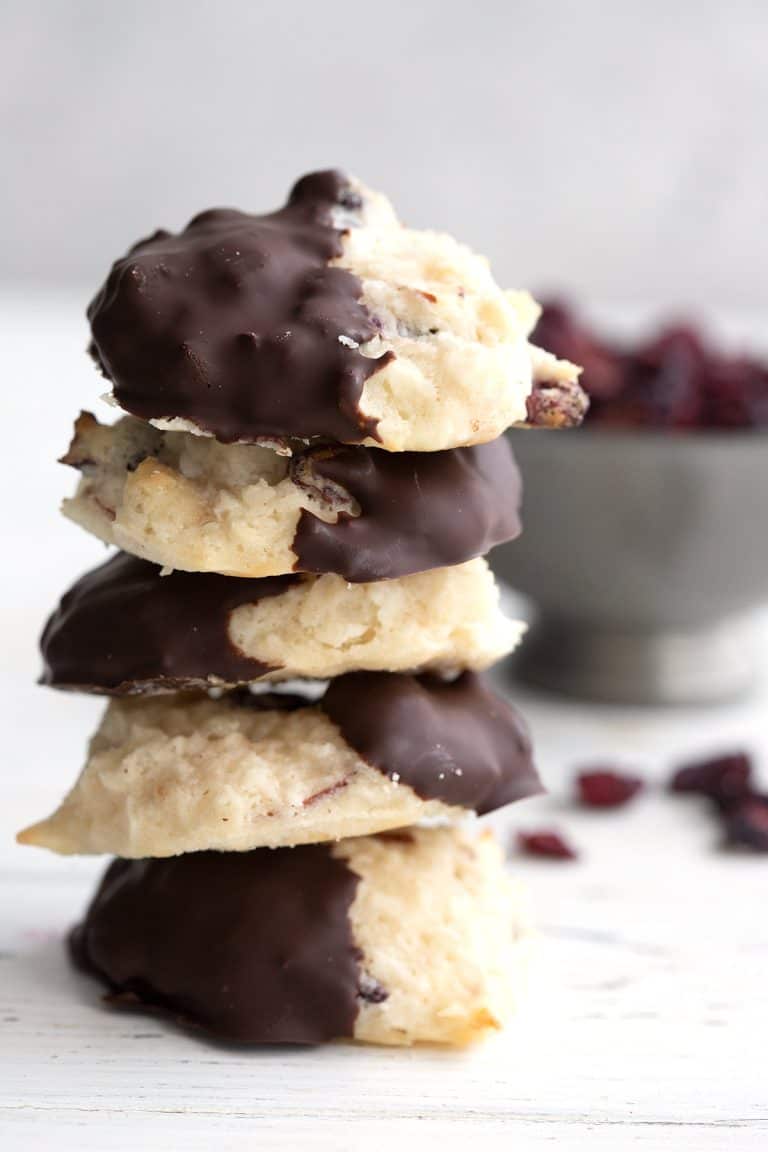 A stack of keto macaroons in front of a bowl of sugar-free dried cranberries.