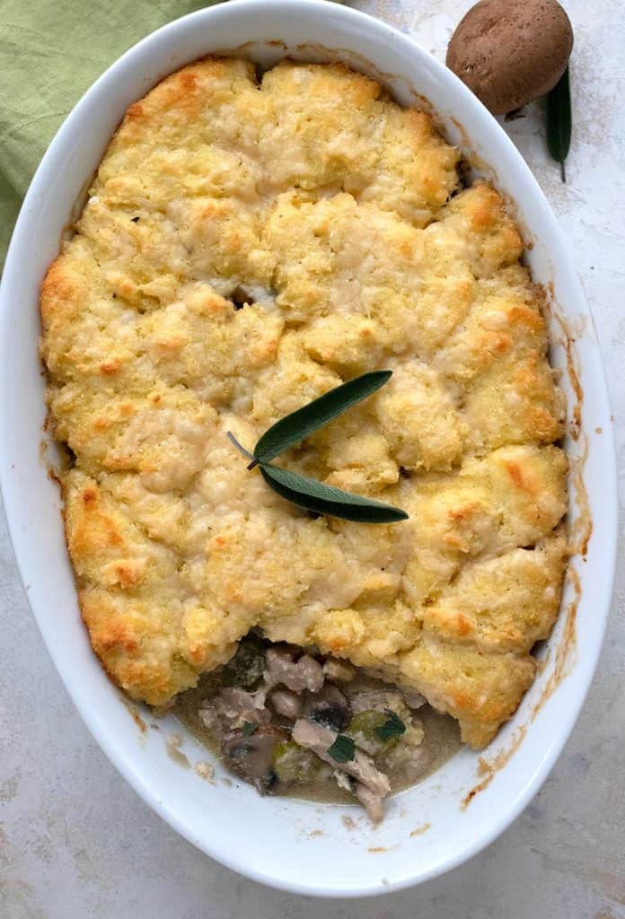 Top down image of keto chicken pot pie with a biscuit crust in a white oval baking dish.