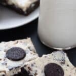 Titled image of Keto Cookies and Cream Brownies on dark table with a bottle of milk in the background.