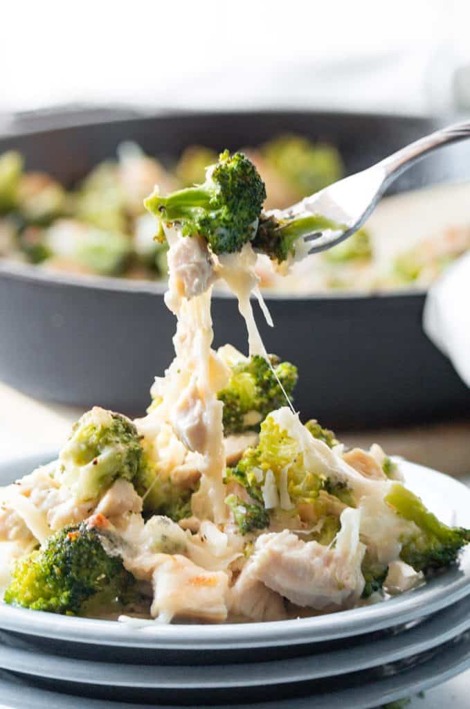 A fork lifting low carb chicken and broccoli off the plate.
