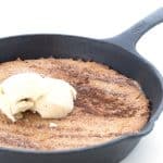 A cast iron skillet full of keto snickerdoodle skillet with ice cream on top.