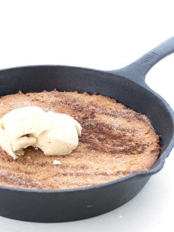 A cast iron skillet full of keto snickerdoodle skillet with ice cream on top.