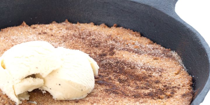 A cast iron skillet full of keto snickerdoodle skillet with ice cream on top.