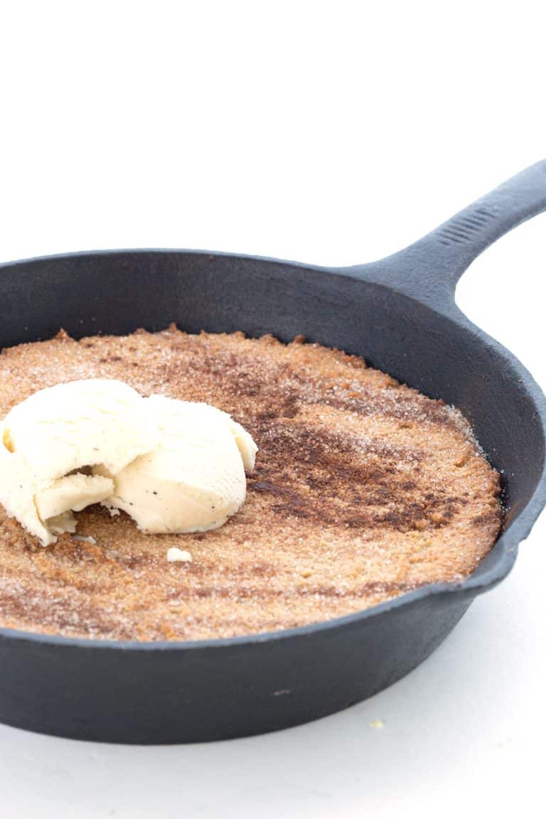 A cast iron skillet full of keto snickerdoodle skillet with ice cream on top.