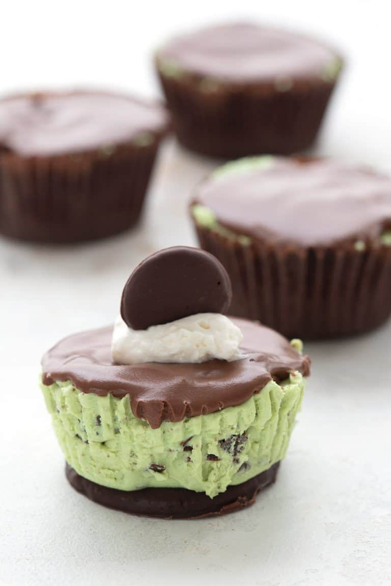 A mini keto thin mint cheesecake on a white table, with more cheesecakes in the background.