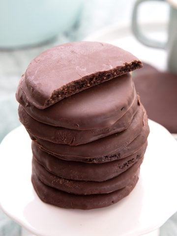 A stack of Keto Thin Mints on a white cupcake stand, with the top one broken open.