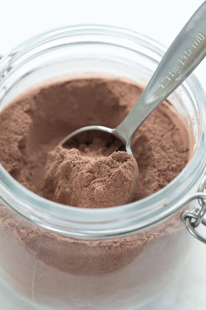 Close up shot of homemade sugar free hot chocolate in a glass jar with a measuring spoon.