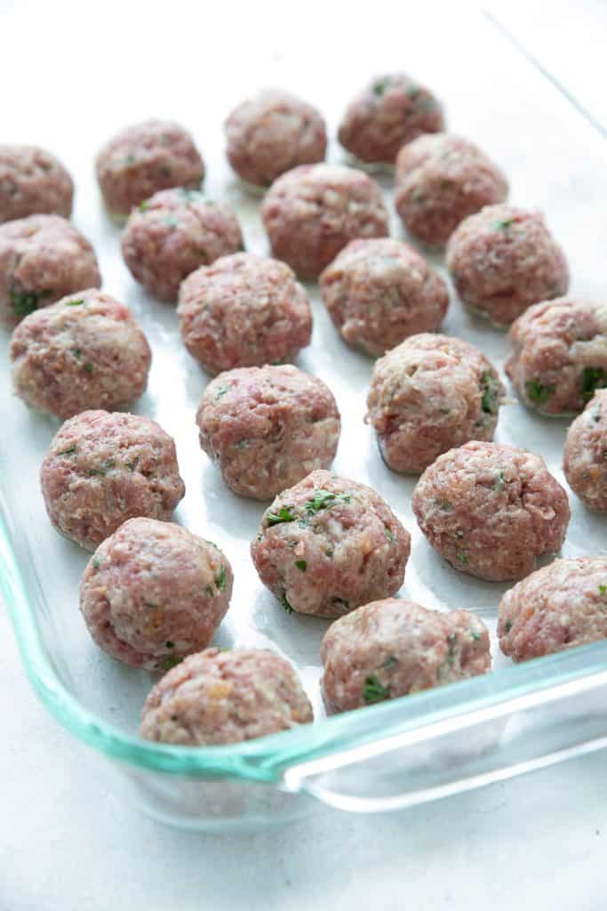 Unbaked keto meatballs in a glass pan.
