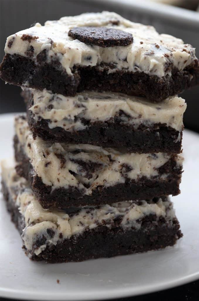 A stack of keto cookies and cream brownies on a white plate with a bite taken out of the top brownie.