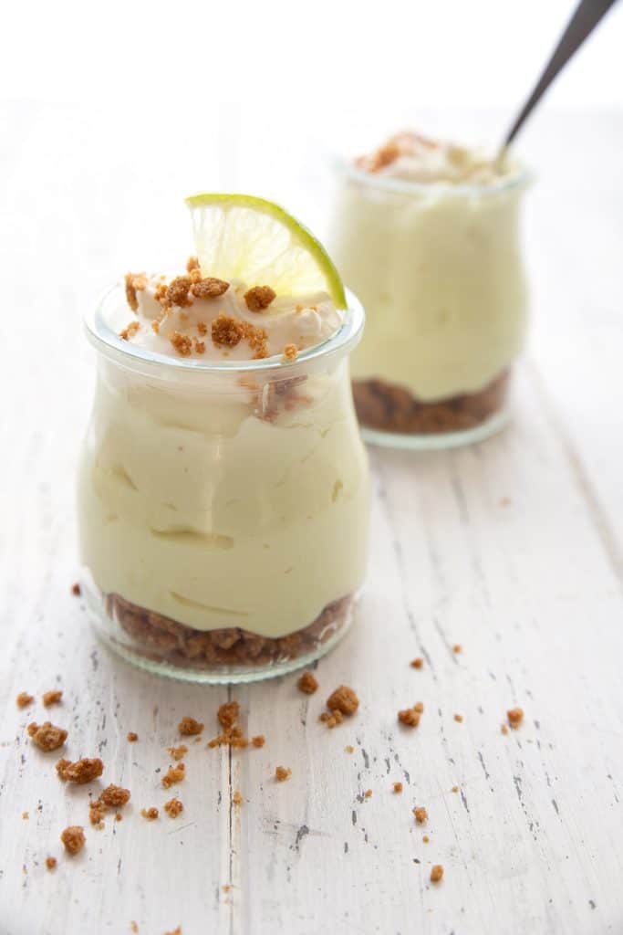 Two jars of no bake keto key lime cheesecake on a white table.