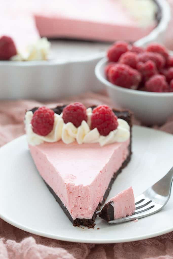 Close up shot of raspberry mousse tart with a forkful taken out of it.
