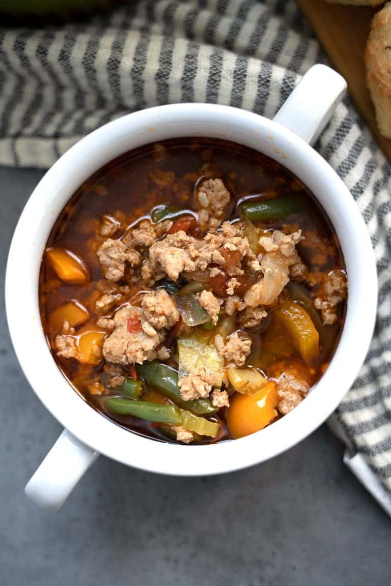 Top down image of keto Italian sausage soup in a white bowl with handles.