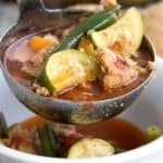 Titled Pinterest image of a ladle of Italian Sausage Soup being poured into a white bowl.