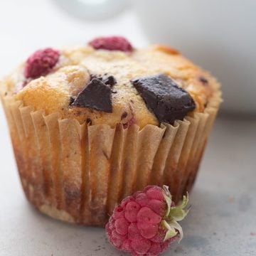 Close up shot of a keto muffin with raspberries and chocolate chunks.