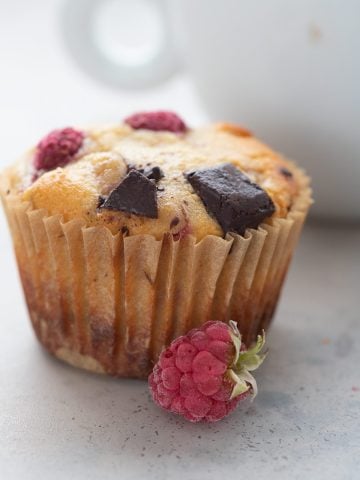 Close up shot of a keto muffin with raspberries and chocolate chunks.