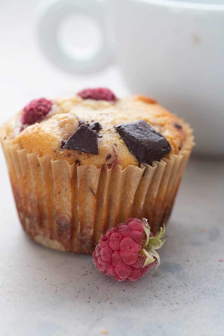 Close up shot of a keto muffin with raspberries and chocolate chunks.