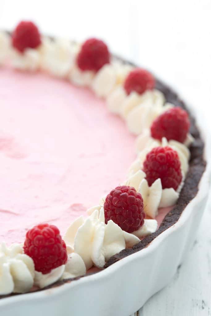 Close up shot of keto raspberry mousse tart in a white ceramic tart pan.