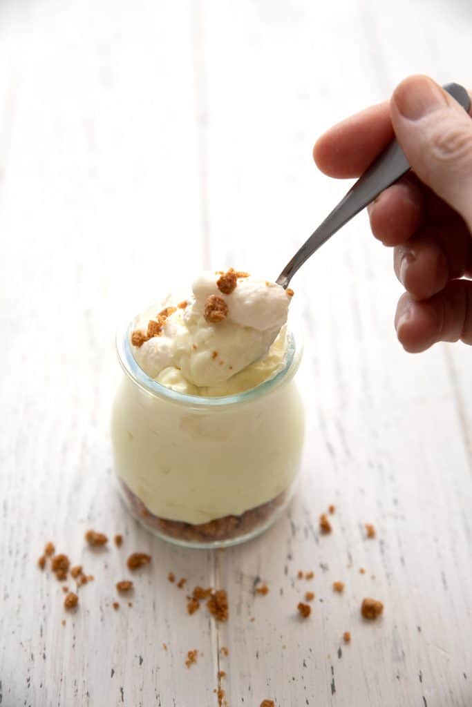 A hand digging a spoon into a jar of easy keto key lime cheesecake.